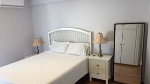 Un dormitorio con cama, mesitas de noche, lámpara, armario y equipo de aire acondicionado.