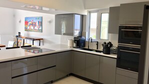Una cocina moderna con armarios grises, horno integrado y cafetera.