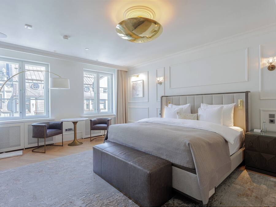 Une chambre moderne avec un grand lit, un banc, un bureau et une chaise.