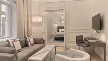 A modern hotel room with a sofa, a desk, a chair, a TV, and a large window.