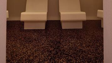 A room with two white cushioned chairs facing each other, a patterned carpet, and a ceiling with multiple recessed lights.