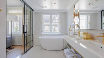 Un baño moderno con una bañera independiente, un espejo grande y un box de ducha de vidrio.