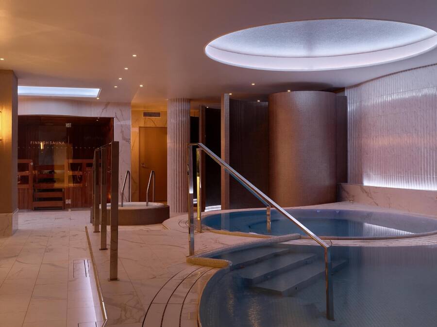 Ein Wellnessbereich mit Whirlpool, einer Treppe und einer Glastür zum Sauna-Bereich.