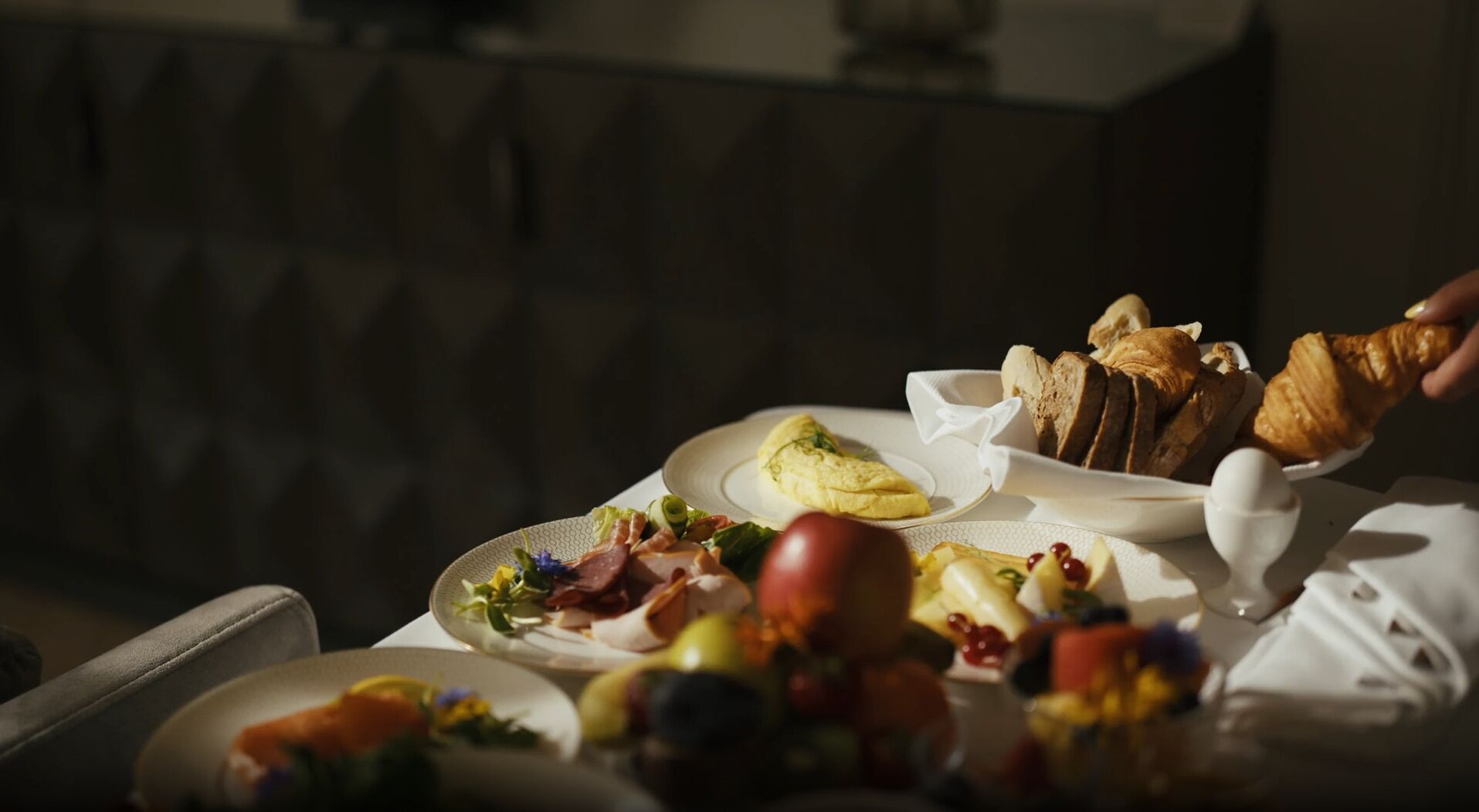 A breakfast table with various foods including eggs, bread, and fruits.