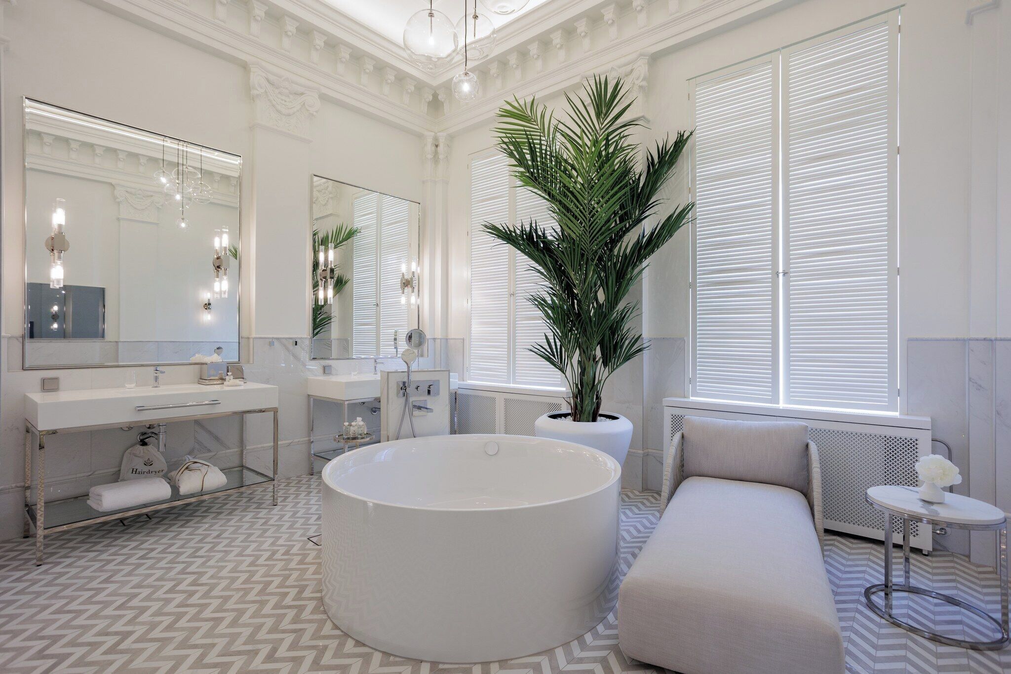 Un baño moderno con una bañera grande, dos lavamanos, un espejo y una planta en maceta.