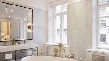 A modern bathroom with a freestanding bathtub, a large mirror, and a vanity with a double sink.