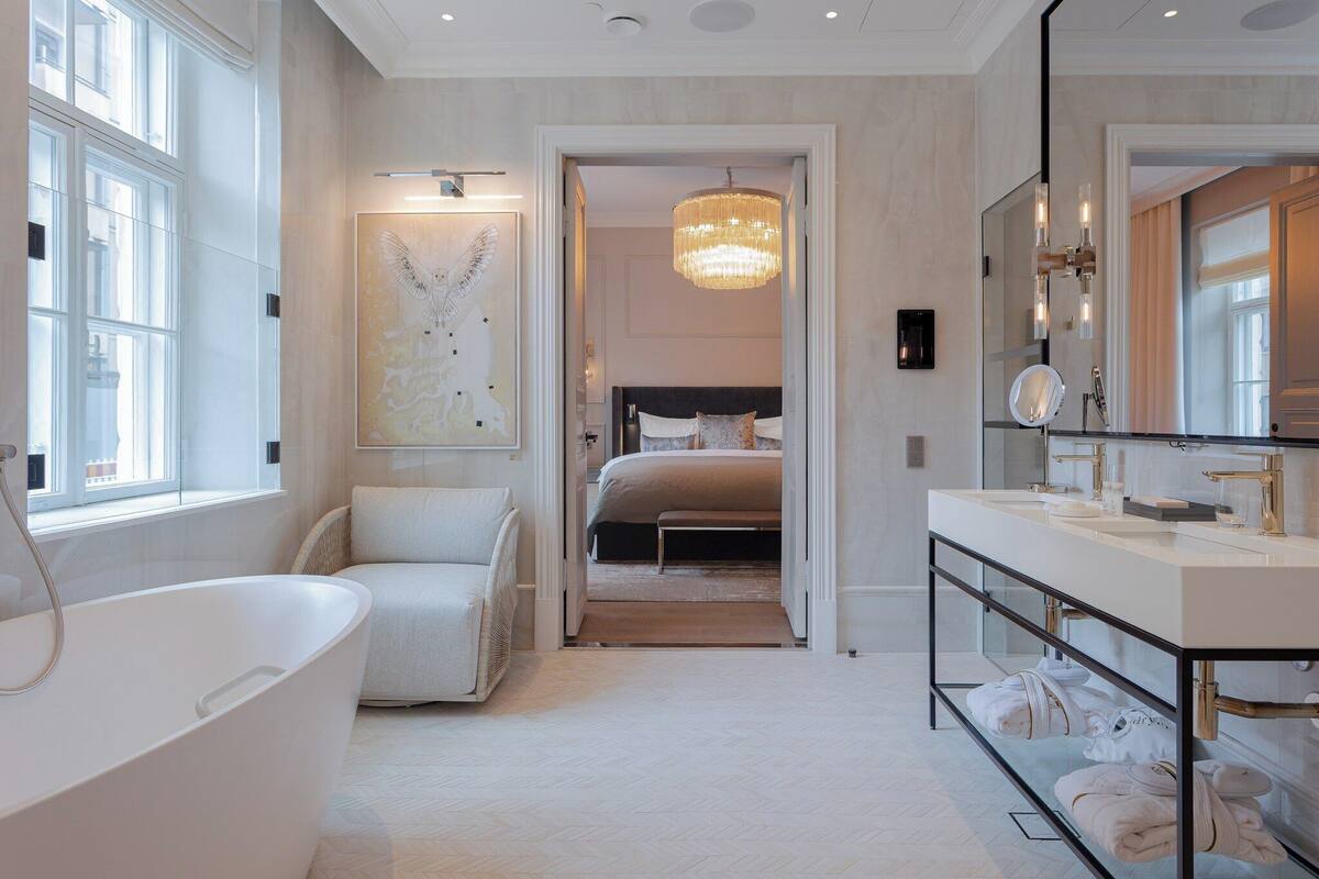 A modern bathroom with a freestanding bathtub, a large mirror, and a chandelier.
