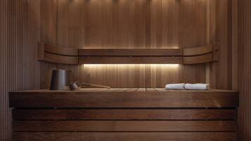 A wooden sauna with a bench, a towel, and a container.