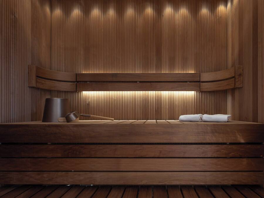 A wooden sauna with a bench, a towel, and a container.
