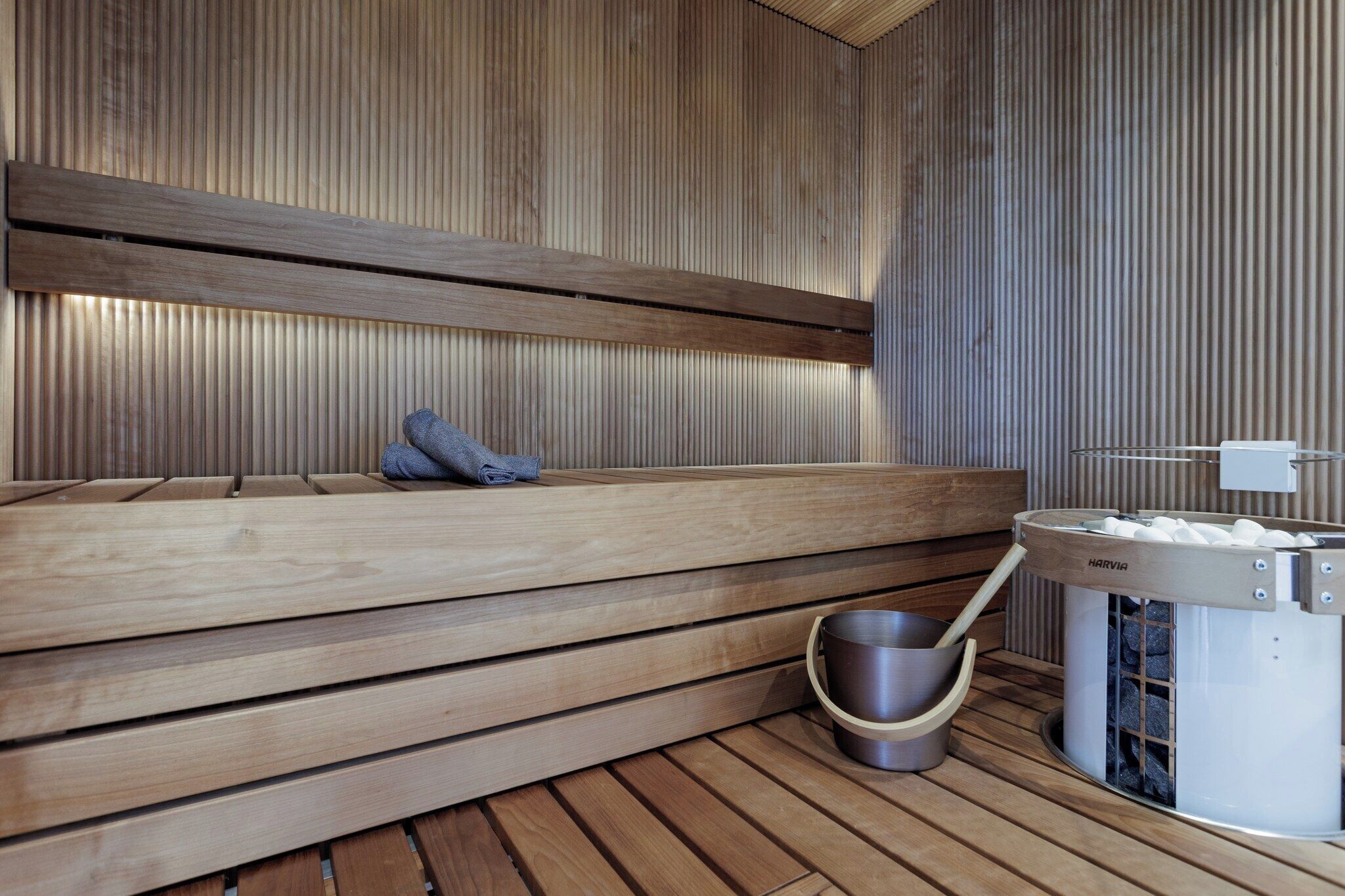 Una sauna con bancos de madera, un recipiente de piedra y un calentador de piedra.