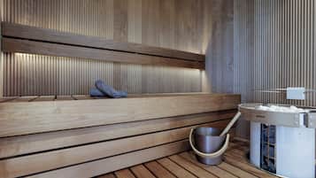 Una sauna con bancos de madera, un recipiente de piedra y un calentador de piedra.