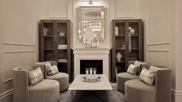 A room with a fireplace, two armchairs, a coffee table, and two bookcases.