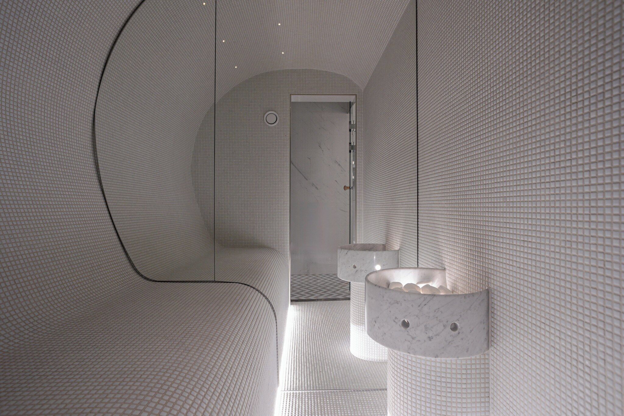 A modern bathroom with a unique geometric design, featuring a curved wall and a circular sink.