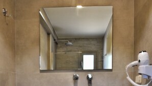 A bathroom with a sink, mirror, towel rack, and a hairdryer. - Liogerma Studios (Kefalonia)