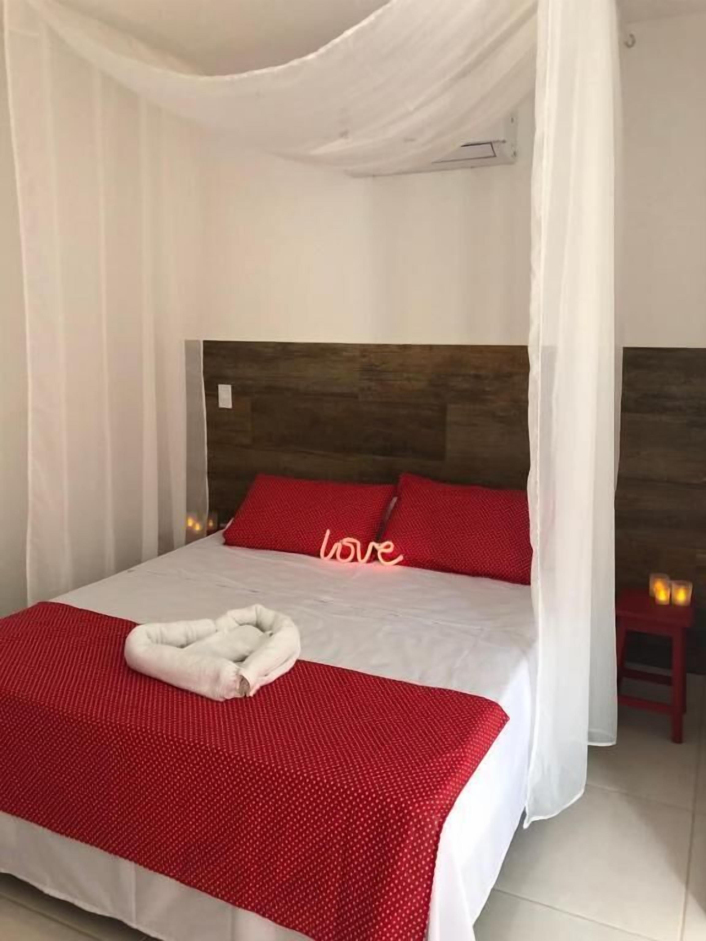 Ein Bett mit weißem Baldachin, roten Kissen und einem Schild mit der Aufschrift 'love'.