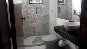 A bathroom with a white tiled floor, a white toilet, a black sink, and a mirror above the sink.