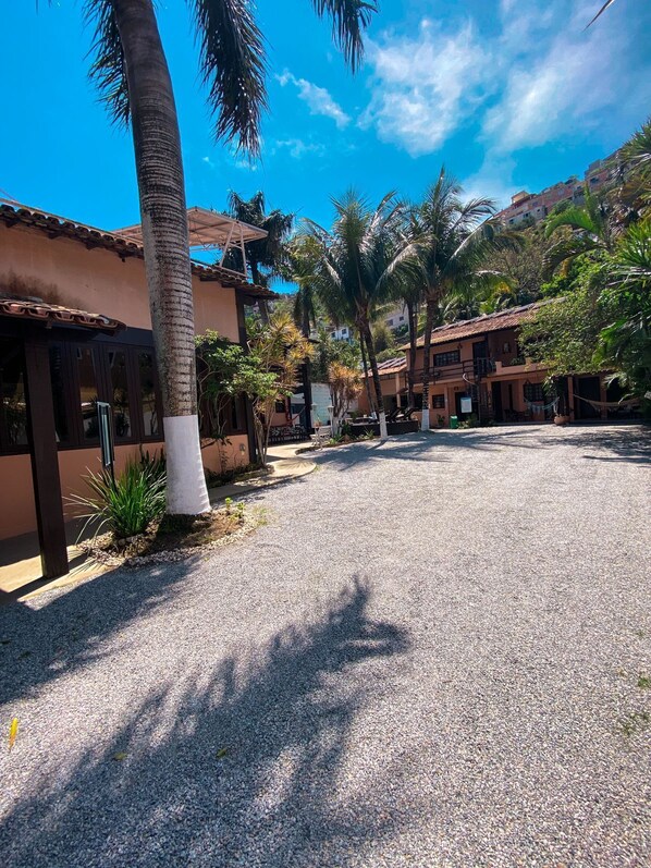 Un patio con palmeras, un camino de grava y edificios con techos de teja.