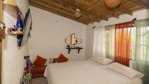 Een slaapkamer met een houten plafond, een bed met witte beddengoed, een spiegel en een plank met decoratieve voorwerpen.