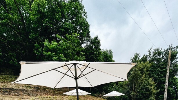 A wooden deck with a pool, outdoor seating, and umbrellas. - Quiet cottages (Prat-Bonrepaux)
