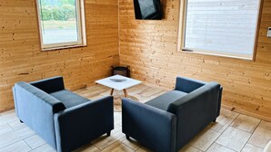 A cozy room with wooden walls, two sofas, a small table, and two windows. - Quiet cottages (Prat-Bonrepaux)