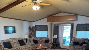 A cozy living room with a wooden dining table, two sofas, a ceiling fan, and a view through a glass door. - Pert-Nere-A-Ranch Hot Tub Teton Views Getaway! (Tetonia)