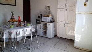 Una cucina compatta con un tavolo da pranzo per due persone, un forno a microonde, un piccolo frigorifero e un armadietto con diverse ante.