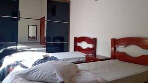 Una camera da letto con due letti, un grande specchio e una sedia di legno.