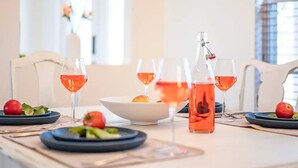 A dining table with a pitcher of pink drink, glasses, plates with food, and a bowl.