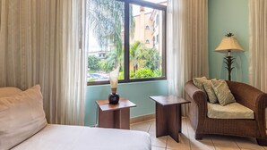 Ein Hotelzimmer mit einem Bett, einer Couch, einem Tisch mit Lampe und einem fenster mit Vorhängen.