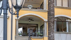 Eine Treppe führt zu einem Balkon mit Sitzgelegenheiten und einer Palme im Vordergrund.