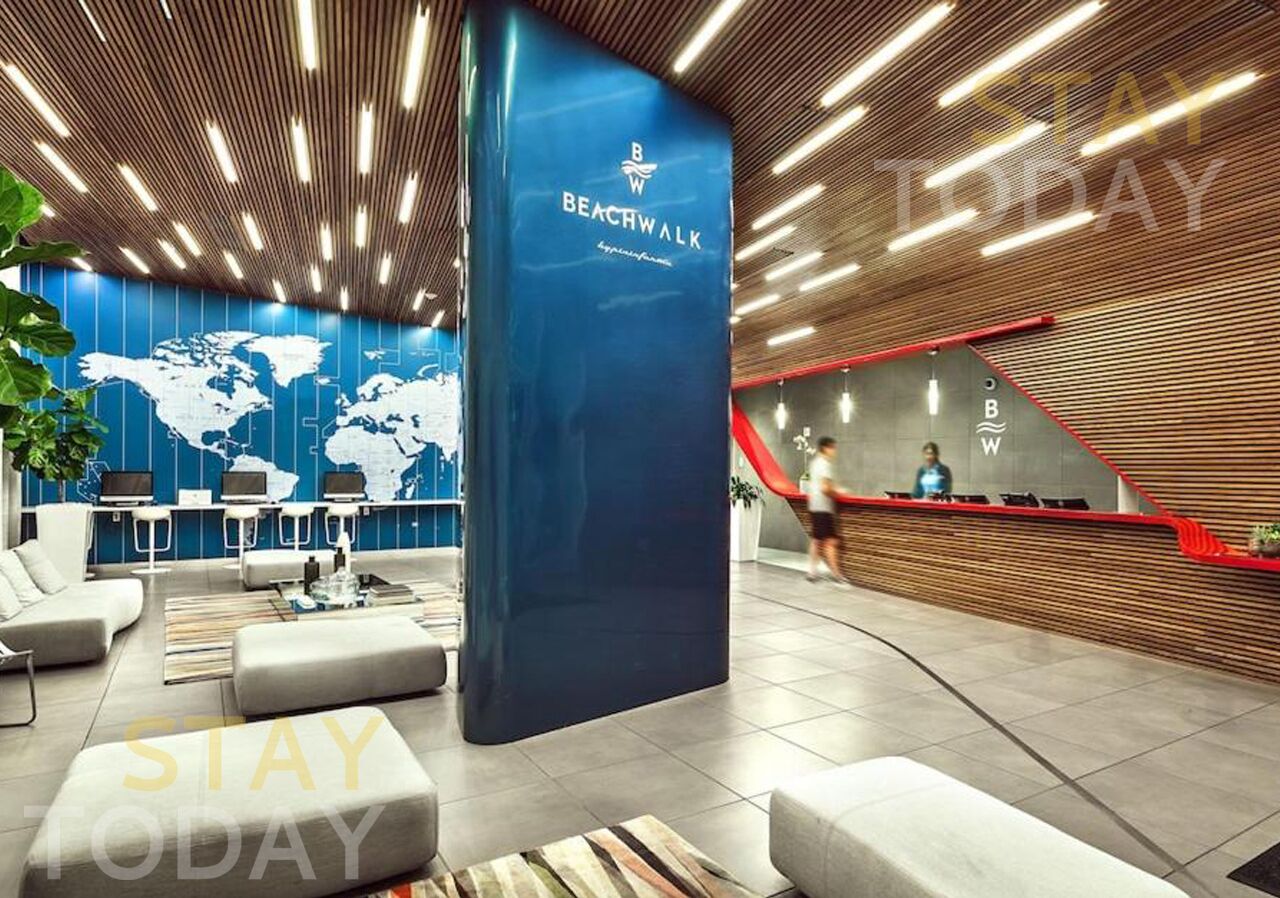 A modern lobby with a world map on the wall, a blue reception desk, and a staircase.