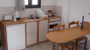 A compact kitchen with a sink, a small oven, a coffee maker, and a dining table with chairs.