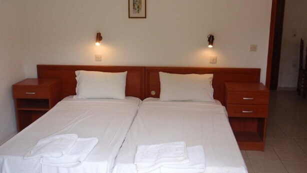A double bed with white linens and two bedside tables, each with a lamp.