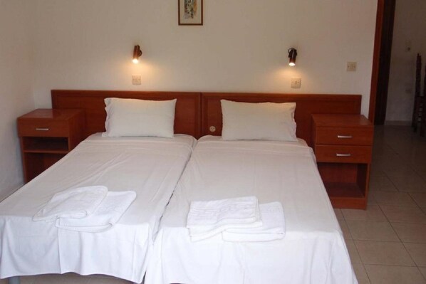 A double bed with white linens and two bedside tables, each with a lamp. - Yianetta Hotel (Corfu)