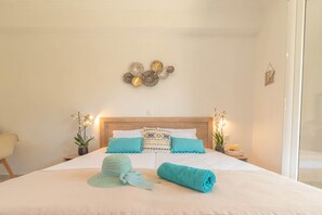 Une chambre d’hôtel comprenant un lit, deux tables de chevet, un élément décoratif fixé au mur et deux plantes en pot.