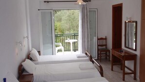 A hotel room with two beds, a balcony with a table and chairs, a wooden dresser, and a mirror.