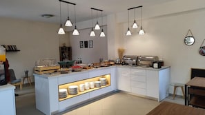 A modern kitchen with a central island, pendant lights, and a buffet setup. - Yianetta Hotel (Corfu)