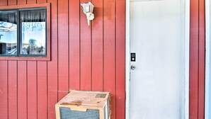 En röd träfasad med en vit dörr och ett fönster.