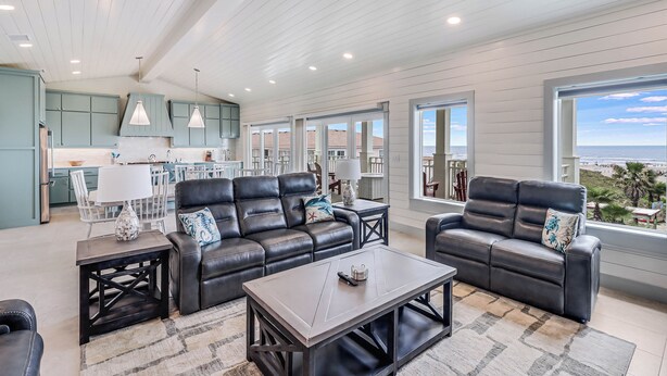 A spacious living area with a modern kitchen, leather sofas, and large windows offering a view of the ocean. - Sandpoint Seaclusion with PRIVATE HEATED POOL,OCEAN VIEWS,ELEVATOR& Beach Access (Port Aransas)