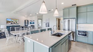 A modern kitchen with a central island, stainless steel appliances, and teal cabinetry. - Sandpoint Seaclusion with PRIVATE HEATED POOL,OCEAN VIEWS,ELEVATOR& Beach Access (Port Aransas)