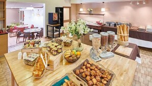 Una mesa de madera con una variedad de alimentos, incluyendo pasteles y frutas, dispuesta para un bufé.