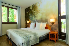 Een slaapkamer met een bed, twee bedlampen, een raam met gordijnen en een muurschildering.