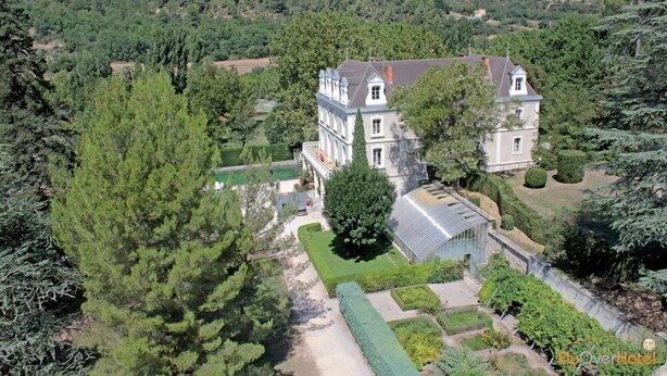 Un edificio grande e histórico con varias secciones y un jardín bien cuidado.