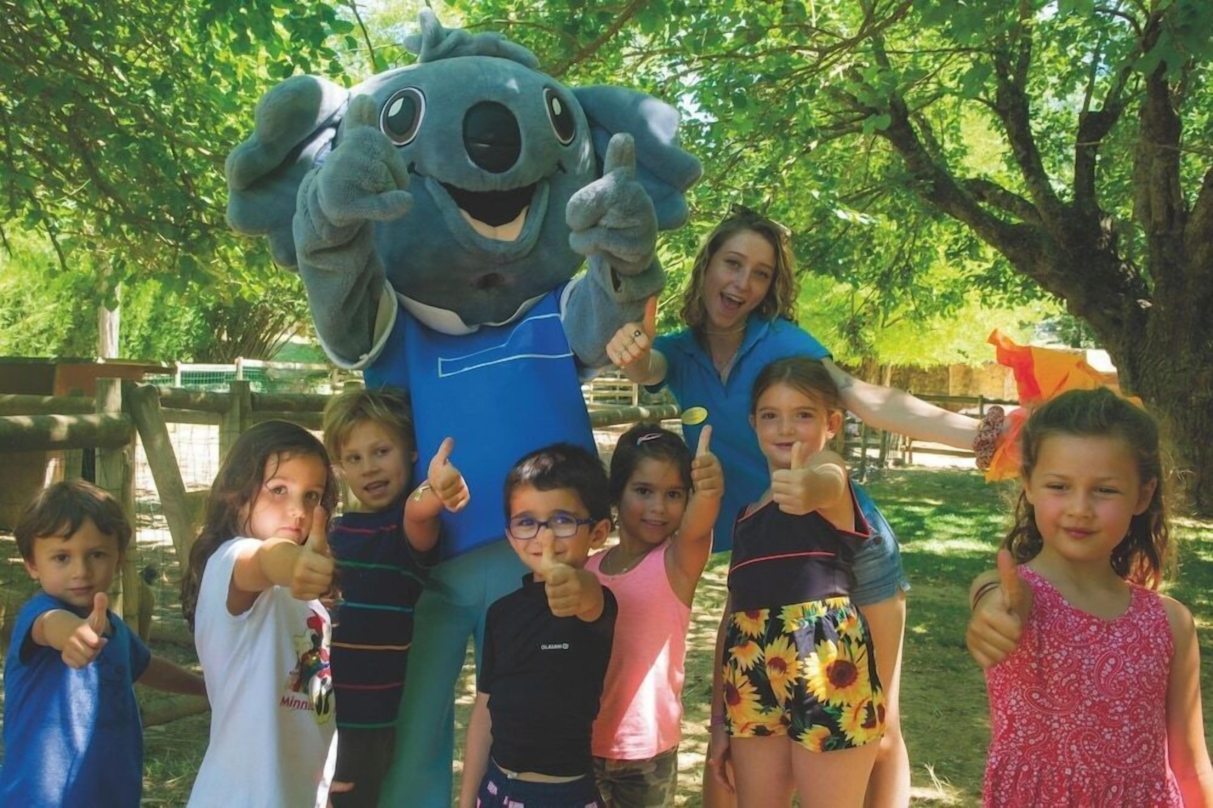 Une mascotte entourée d’un groupe d’enfants qui lèvent tous le pouce en signe d’approbation.