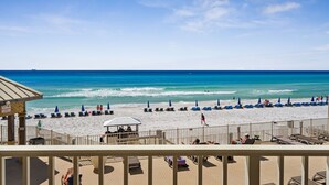 Une plage avec des chaises longues et des parasols, une tour de surveillance pour les sauveteurs, et une vue dégagée sur l’océan.