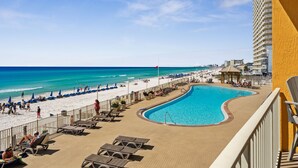 Un espace piscine d’un complexe hôtelier offrant une vue sur la plage et l’océan.