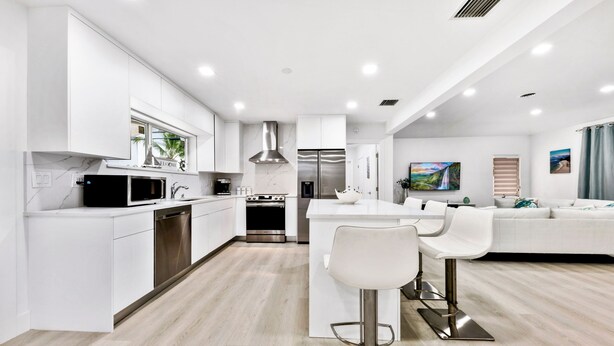 A modern kitchen with white cabinetry, stainless steel appliances, and a central island with bar stools. - The perfect Vacation next to the Ocean in the heart of Fort Lauderdale Beach. (Fort Lauderdale)