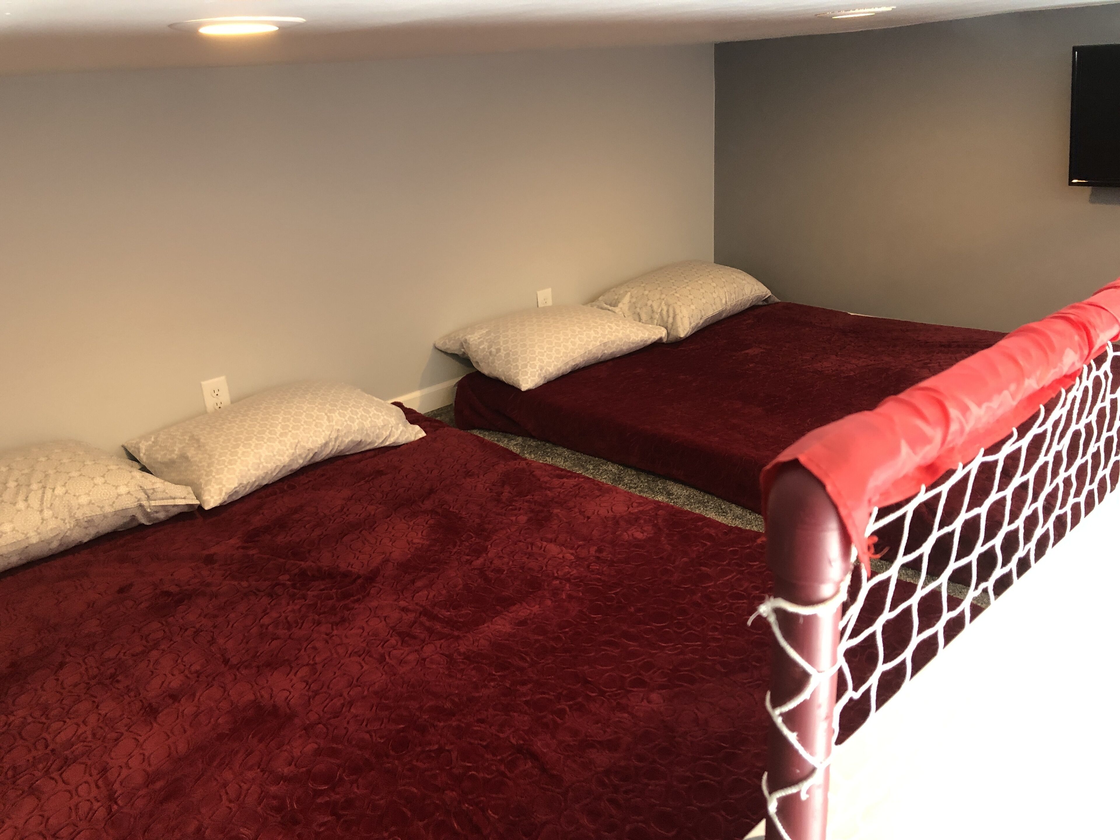 A room with two beds, each with a red bedspread and white patterned pillows.