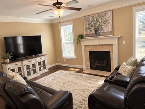 A living room with a fireplace, a television, and leather sofas.