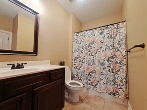 A bathroom with a white sink, dark wooden cabinets, a toilet, and a floral shower curtain.